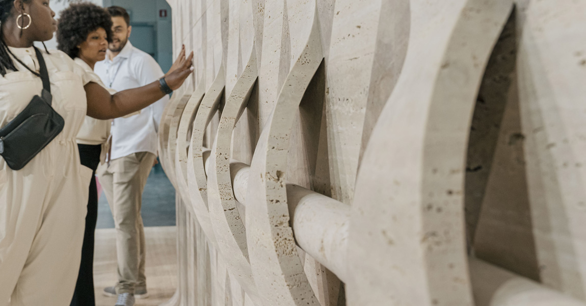 Pessoa em um estande da Marmormac na Itália analisando uma peça em exposição